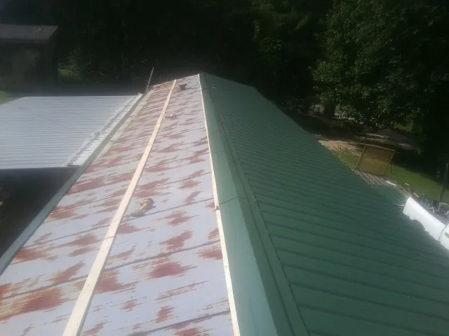 Old rusted panels beside newly installed green metal roofing — Wind Damage Roof Repair by Roofing Brothers in Haysville