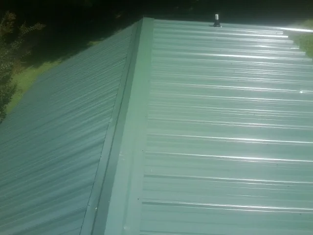 New green metal panels meeting at the ridge of a roof — Flat Roof Repair work by our crew in Haysville