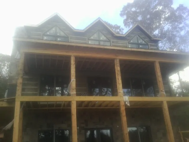 Dormers and porch framing on a large log home under construction — Roof Coating work by our crew in Haysville