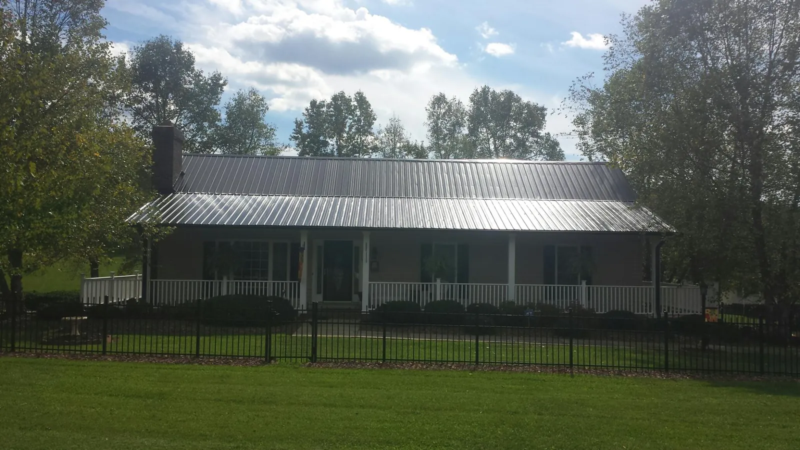 Gray metal roof on a brick ranch with a full width front porch — Gutter Guard Installation work by our crew in Haysville