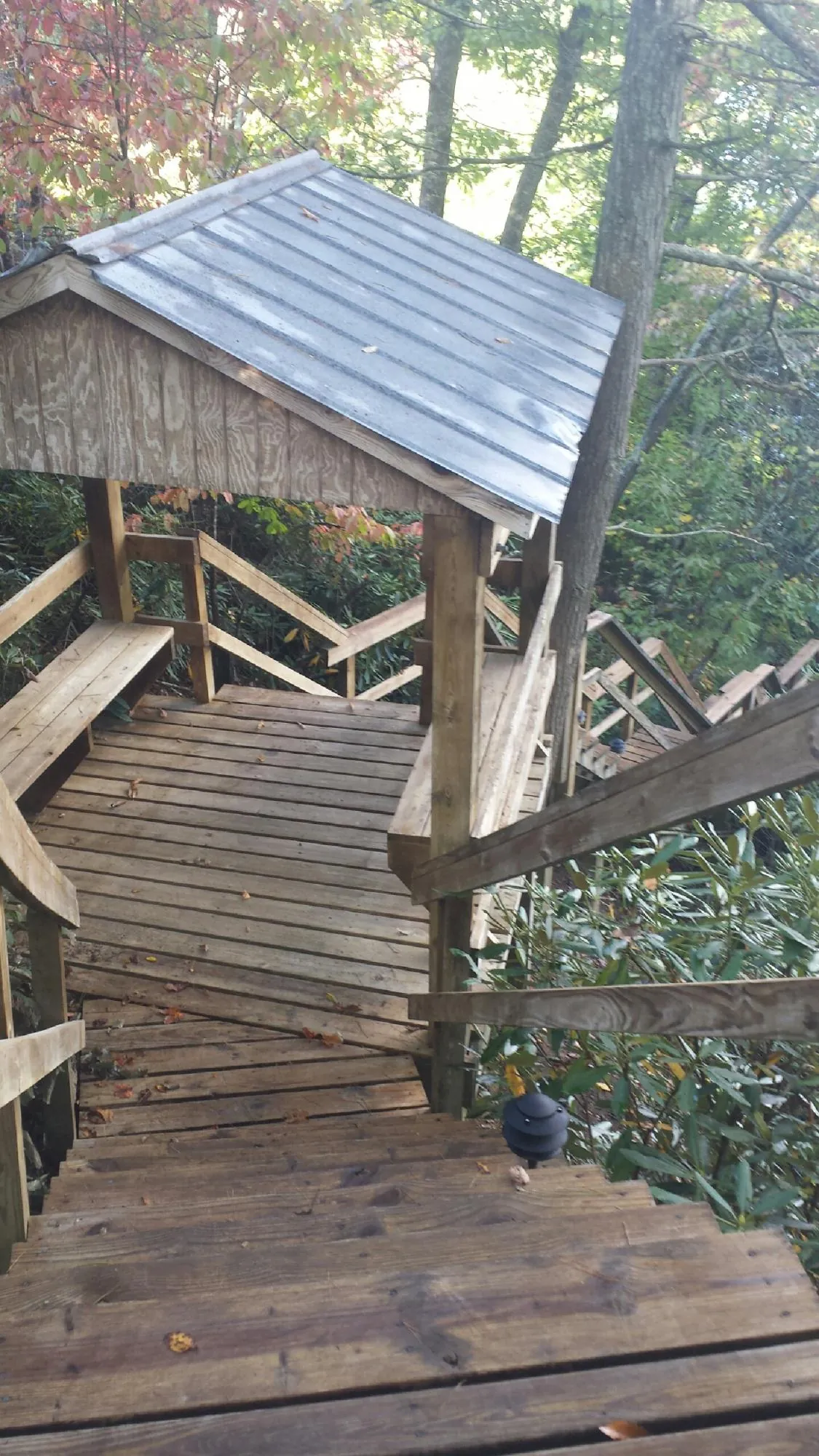Metal roofed shelter over wooden steps on a wooded walkway — Skylight Repair & Installation work by our crew in Haysville