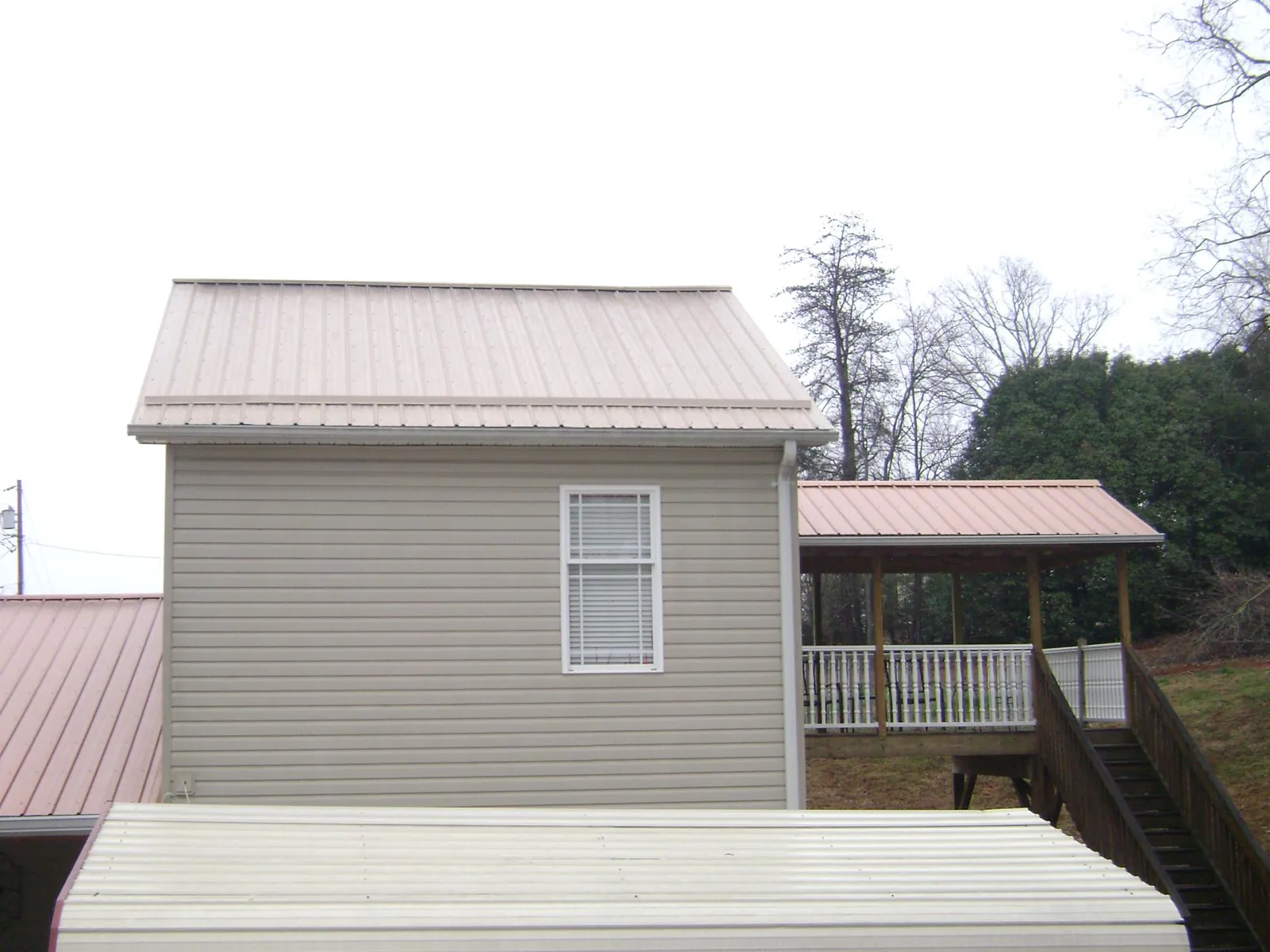 Tan metal roofs on a two story addition and attached porch, from a Roof Replacement job in Haysville