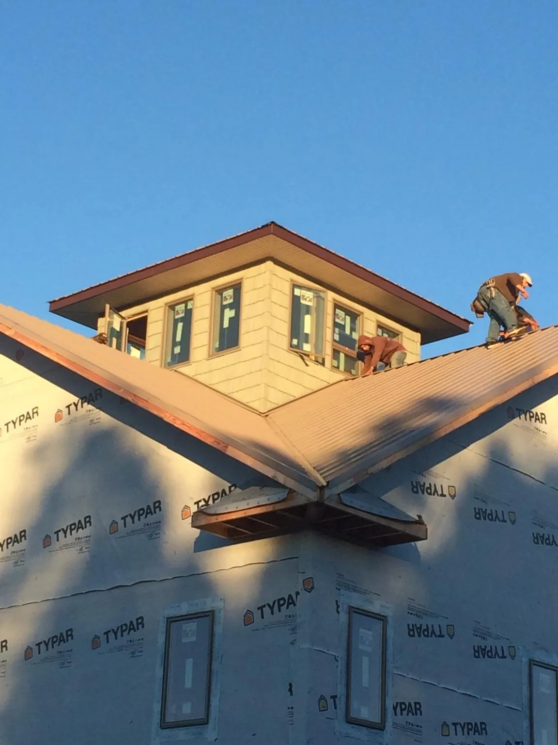 Roofers working around a rooftop cupola on a new metal roof at sunset — Roof Waterproofing in Haysville by Roofing Brothers